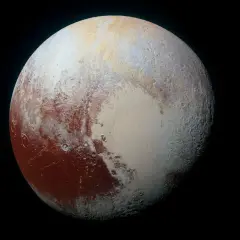 Pluton w całej okazałości, z czerwonymi i białymi plamami na powierzchni, unoszący się w czerni kosmosu.