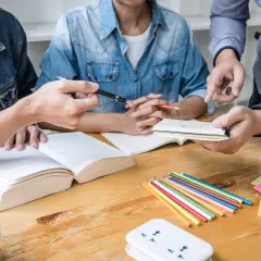 Studenci dyskutują o empiryzmie, co to jest, analizując książki i notatki. Kolorowe kredki i karteczki sugerują burzę mózgów.