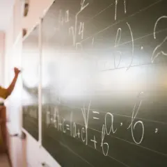 Nauczyciel dyplomowany pisze wzory matematyczne na tablicy.