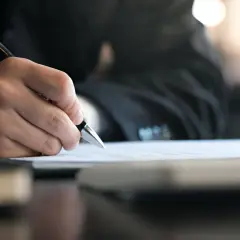 Dłoń pisze piórem na dokumencie. Czekam, póki skończę ważną umowę.