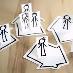 Proste rysunki postaci na domkach symbolizują inkluzję i wspólnotę.
