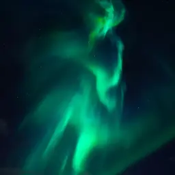 Zielona zorza polarna tańczy na nocnym niebie, przypominając o kosmicznej metafizyce i tajemnicach wszechświata.