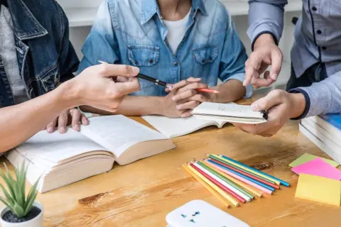 Studenci dyskutują o empiryzmie, co to jest, analizując książki i notatki. Kolorowe kredki i karteczki sugerują burzę mózgów.
