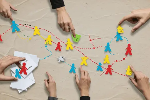 Ręce układają kolorowe papierowe ludziki, tworząc ścieżki. To jak gra, w której dzieci uczą się współpracy i planowania.