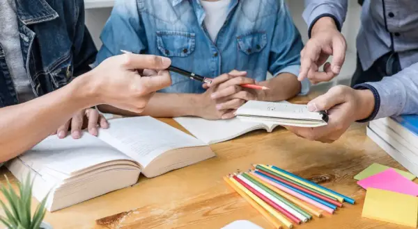 Studenci dyskutują o empiryzmie, co to jest, analizując książki i notatki. Kolorowe kredki i karteczki sugerują burzę mózgów.