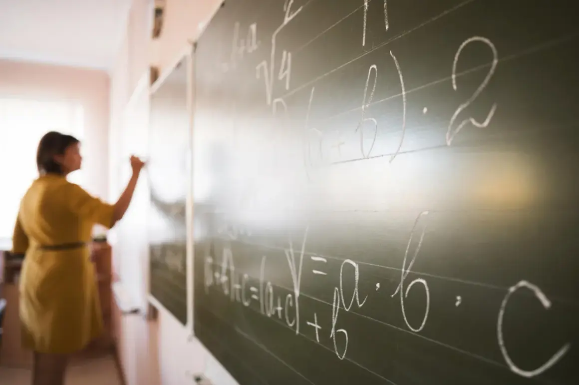 Nauczyciel dyplomowany pisze wzory matematyczne na tablicy.