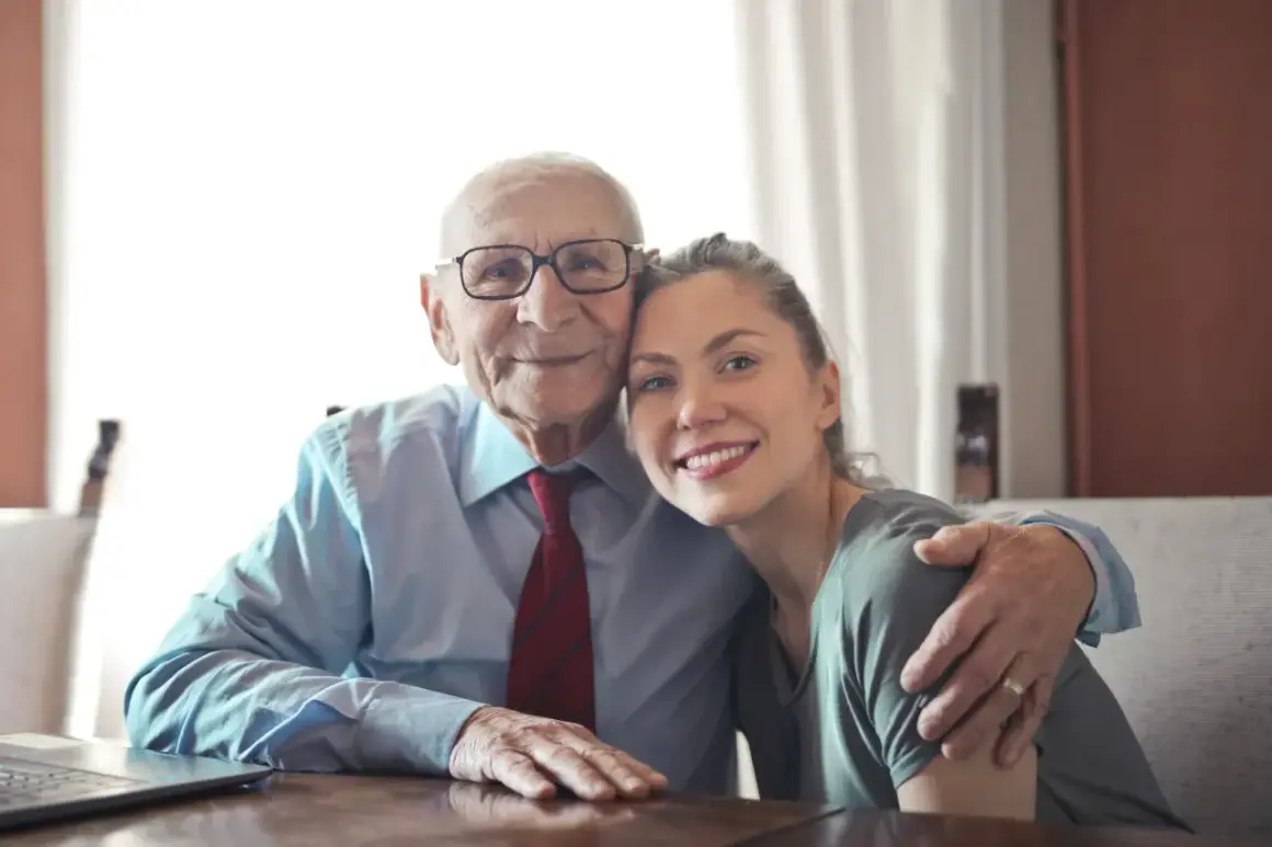 Uśmiechnięty starszy pan z wnuczką, uosobienie łączących pokolenia ludzi.